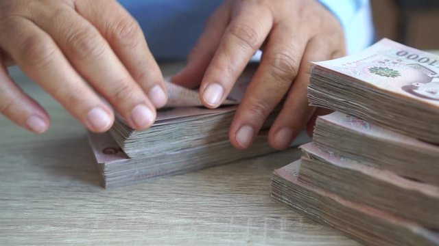 Stack Thai baht banknotes, Businessman's hands counting money. one thousand baht with tag text in Thai word. (THB) is official currency of Thailand. Finance and banking business in Asia concept