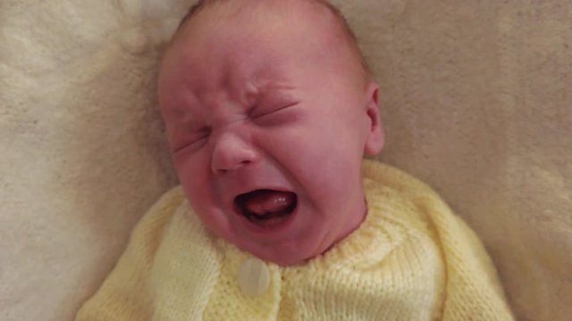 Close up of an upset young newborn baby crying