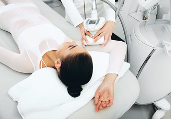 Beautician doing LPG massage on the hand of a beautiful woman. Removing sagging skin on the arm and...
