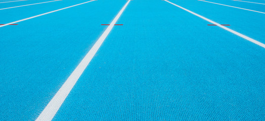 Blue running track with white lines and red mark in sport stadium. Top view