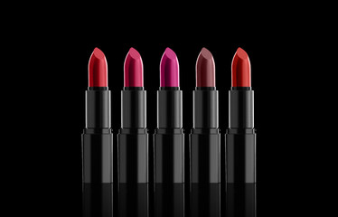 A few bright lipsticks, sparkles on a dark background. Horizontally