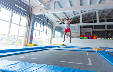 Fitness, fun, leisure and sport activity concept - Handsome happy man jumping on a trampoline...