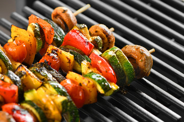 Barbecue vegetable skewers on a dark background from mushrooms, tomato, zucchini, pepper, buttery, bright, vegetarian. Dark background. Horizontally.