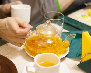 Man pours sea buckthorn tea from a teapot