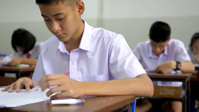 The Asian high school students in white uniform are doing examinations.
