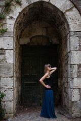 Gorgeous young woman standing at old wooden door. Stylish girl enjoying time. 