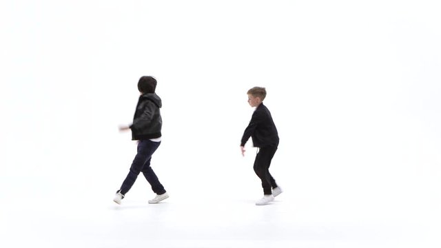 Little boys are dancing a modern dance on the white background in black leather jackets and jeans