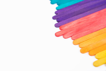 Colorful rainbow wooden popsicles on white paper background with copy space, abstract color sticks cover frame for children art craft works, kids back to school concept