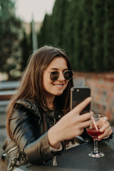 Young woman making self portrait using smartphone. Girl making selfie. Woman in cafe. Woman alone. Self portrait in cafe outdoors. smile. smilimg. gadget. self portrait. coffe break. coffee time