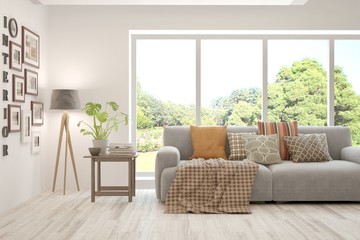 Fototapeta premium Stylish room in white color with sofa and summer landscape in window. Scandinavian interior design. 3D illustration