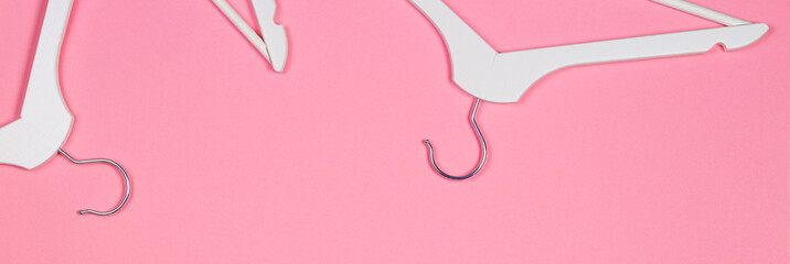 White wooden clothes hangers on pastel pink background. Shopping, sale, promo, new season concept
