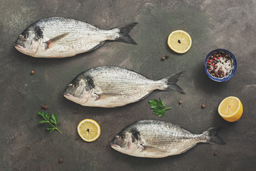 Flat lay three raw fresh dorado fish on a dark painted background. View from above.