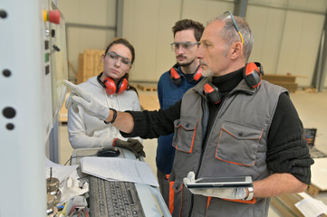 Carpenter with apprentice working in workshop