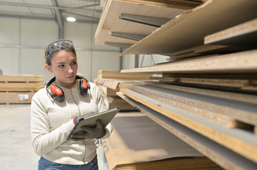 Young woman apprentice working in woodwork warehouse