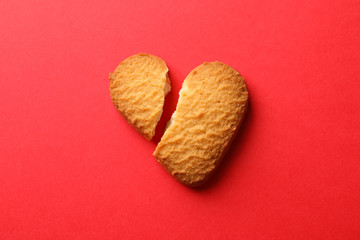 Broken heart shaped cookie on red background, close up