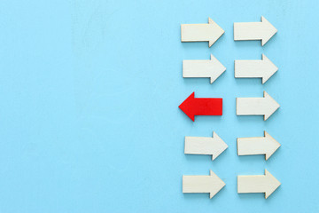 Concept image of red arrow facing opposite direction from other arrows in group. Individuality and...