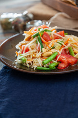 Traditional Thai food papaya salad prepared with fine slices of papaya, tomatoes, green beans and peanuts.