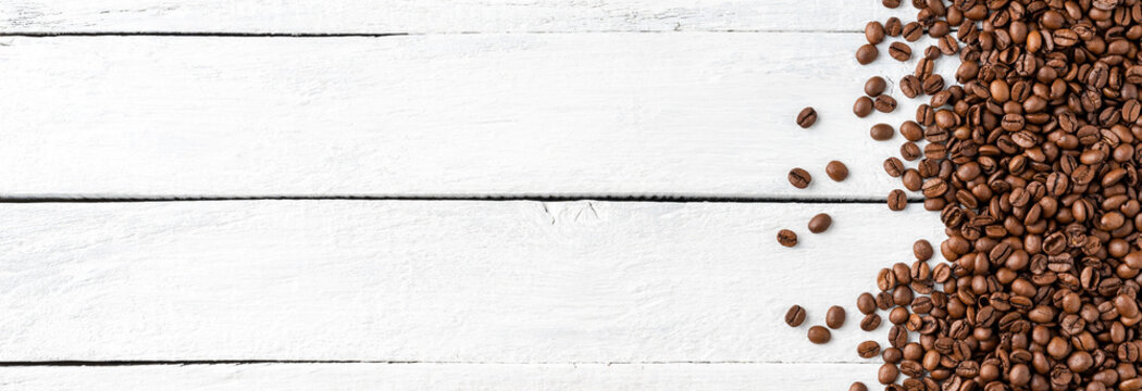 Aromatic coffee beans on white wooden table. Top view. Banner © One Pixel Studio