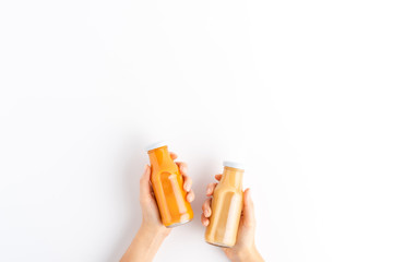 Female hands holding bottles of fruit and vegetable smoothies isolated on white background with copyspace. Top view