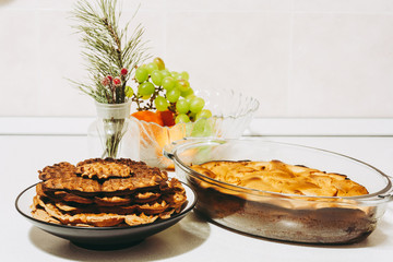 Homemade apple pie - charlotte. Home cooking waffles and apple cake in the form of a baking dish. Freshly Baked Charlotte and vase with Grapes and oranges