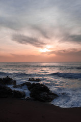 Fototapeta na wymiar Sunset over the ocean, waves break down to rocks in the water