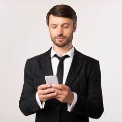 Confident Businessman Using Cellphone Texting Over White Background