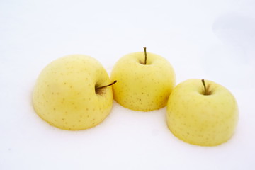 Yellow melba apples on white snow close-up