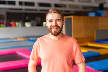 Fitness, fun, leisure and sport activity concept - Man smiling on a trampoline indoors