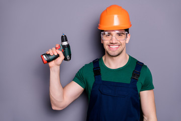 Portrait of confident cool man repairer hold perforator ready to renew flat apartment wear blue overalls green t-shirt isolated over grey color background