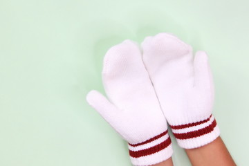 Two hands in white mittens isolated on a light background