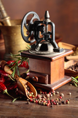 Vintage pepper mill with kitchen utensils, spices and rosemary.