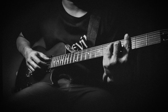 Close up view of man's hands playing electric guitar. Black and white picture