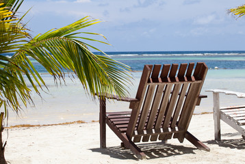 Relaxing place on a tropical beach with sun chair under a palm tree