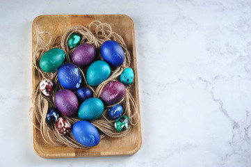 Easter eggs on a wooden tray. Eggs are green, blue and purple. View from above. Close-up. Free space for text.
