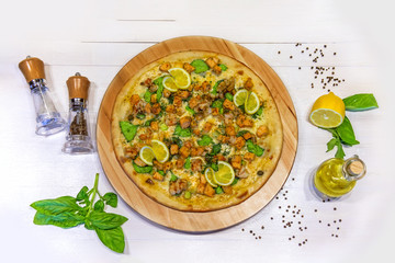 pizza with prawns, lemon, olive oil and spices on a white background, flat lay
