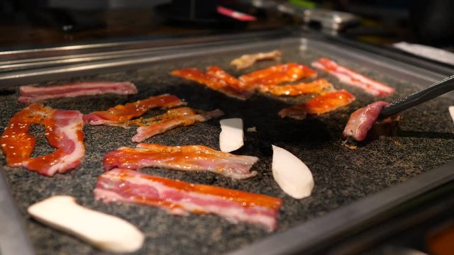 Close-up of woman's hand coocking korean barbecue in a restaurant