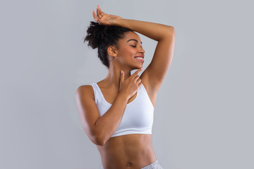 Happy afro girl smelling her armpit over grey background