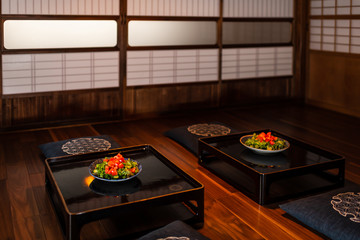 Traditional Japanese house or ryokan restaurant room with two green lettuce salad plates on table,...