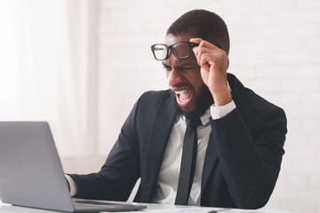 Angry entrepreneur looking at laptop screen and shouting