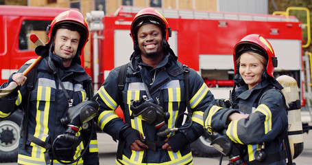 Portrait of group firefighters standing near fire truck. Firefighters in protective suit with...