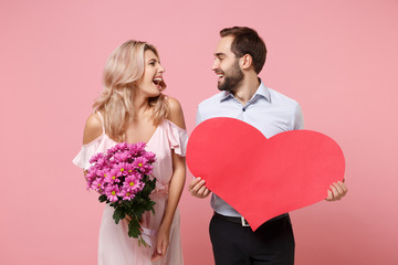 Laughing young couple two guy girl in party outfit celebrating posing isolated on pink background....