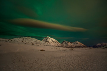 Dramatic polar lights, Aurora borealis with many clouds and stars on the sky over the mountains in the North of Europe - Tromso, Norway.long shutter speed.