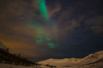 Dramatic polar lights, Aurora borealis with many clouds and stars on the sky over the mountains in the North of Europe - Tromso, Norway.long shutter speed.