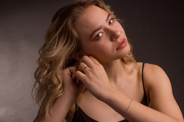 Studio portrait of blonde on a dark background in a dark dress