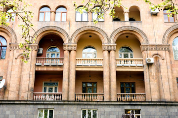 Fragment of building with small balconies with arches, columns and stone carvings. Yerevan, Armenia