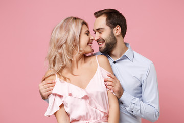 Pretty young couple two guy girl in party outfit celebrating isolated on pastel pink background. People lifestyle Valentine's Day, Women's Day birthday holiday party concept. Looking at each other.
