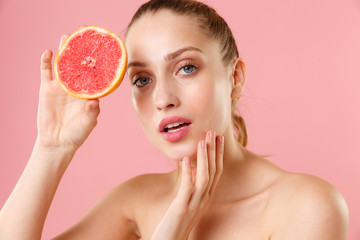 Close up blonde half naked woman 20s perfect skin nude make up blue eyes hold in hand grapefruit...
