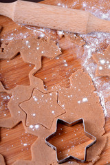 Shortbread dough for gingerbread cookies is rolled on the wooden board. Cutting star cookies