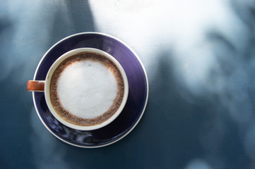 A cup of coffee on wooden background with copy space.Hot coffee has bubble on top.