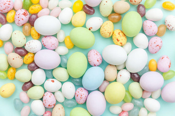 Happy Easter concept. Easter candy chocolate eggs and jellybean sweets isolated on trendy pastel blue background. Simple minimalism flat lay top view copy space